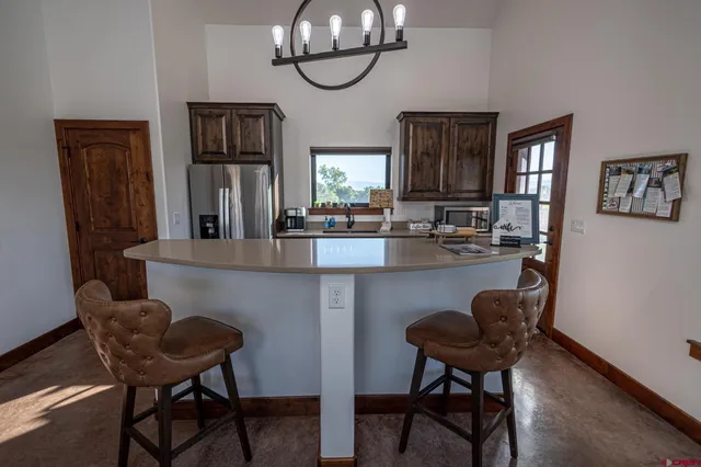 a kitchen with stainless steel appliances a dining table chairs and refrigerator