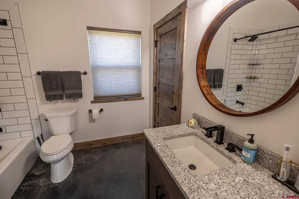 a bathroom with a granite countertop toilet sink and mirror