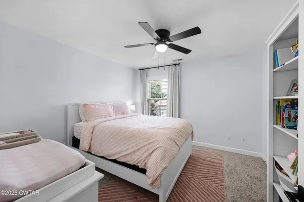 a bedroom with two beds and ceiling fan