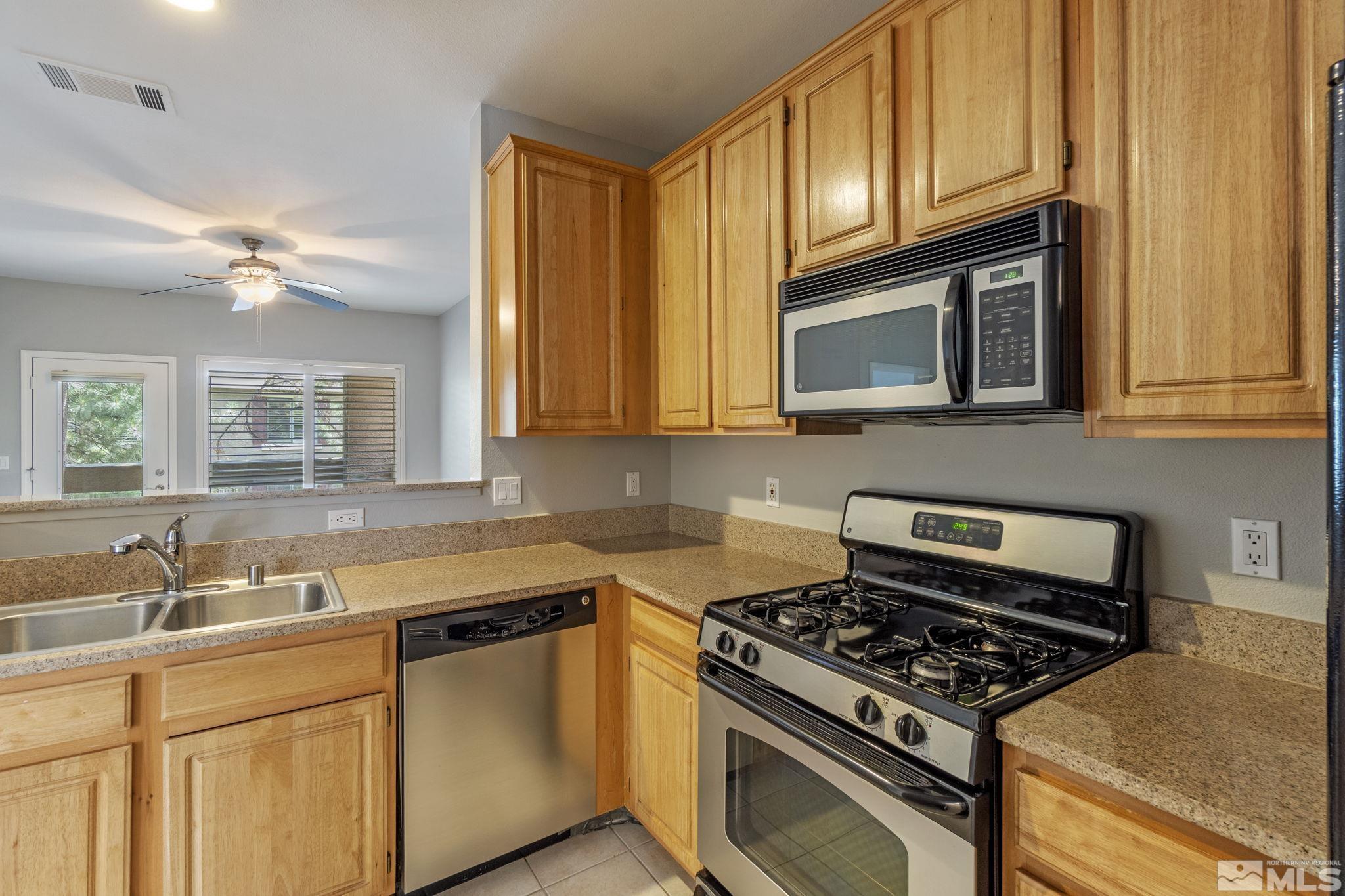 900 South Meadows Parkway, Unit 223 Reno, NV 89521 - Photo 7 of 40 a kitchen with stainless steel appliances granite countertop a stove and a microwave