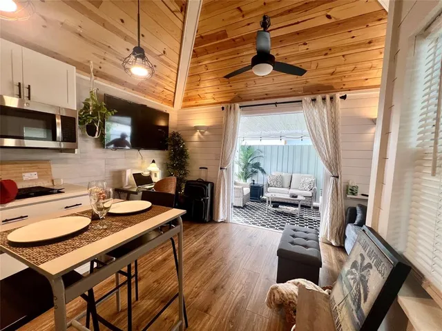 a kitchen with stainless steel appliances granite countertop a stove a sink dishwasher a dining table and chairs with wooden floor