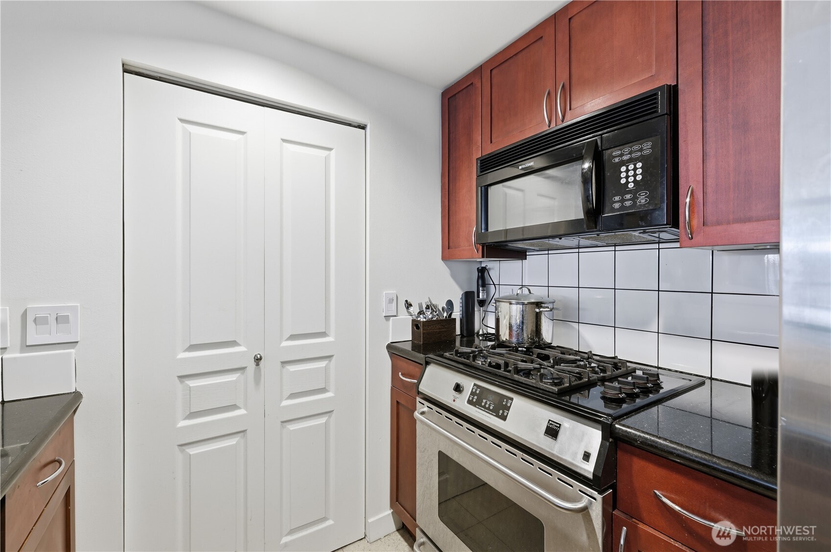 2929 1st Avenue, Unit 201 Seattle, WA 98121 - Photo 12 of 35 a kitchen with granite countertop cabinets and steel stove top oven
