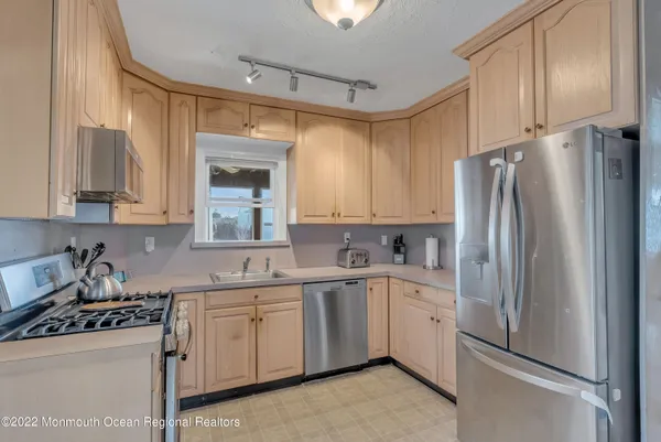 a kitchen with white cabinets and refrigerator
