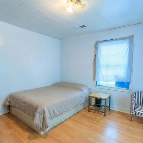 a bedroom with a bed a table and windows