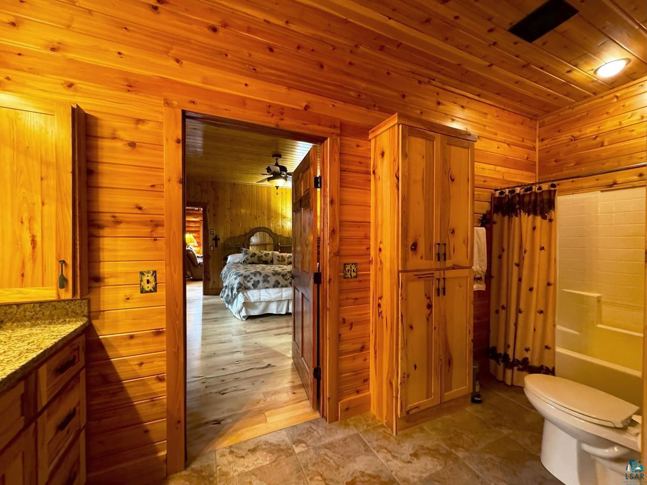 7236 Far North Road Orr, MN 55771 - Photo 11 of 42 Bathroom with wooden walls, toilet, shower / tub combo, vanity, and wood ceiling
