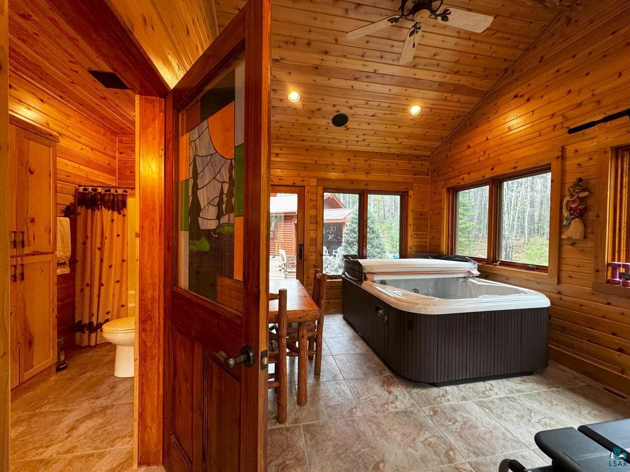 7236 Far North Road Orr, MN 55771 - Photo 12 of 42 Bathroom featuring lofted ceiling, ceiling fan, toilet, wooden walls, and wooden ceiling