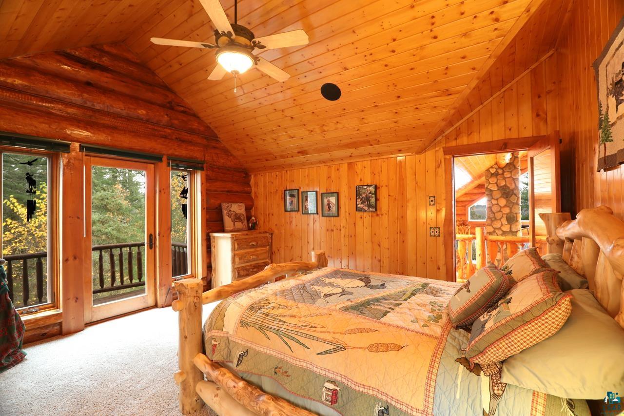 7236 Far North Road Orr, MN 55771 - Photo 15 of 42 Bedroom featuring lofted ceiling, carpet flooring, access to outside, wood walls, and wood ceiling