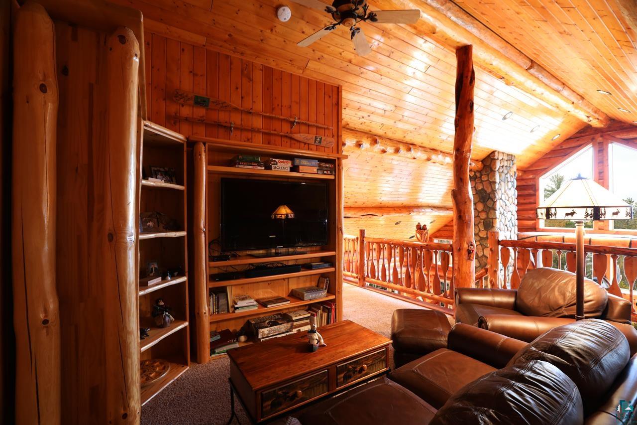 7236 Far North Road Orr, MN 55771 - Photo 16 of 42 Carpeted living area featuring log walls, ceiling fan, vaulted ceiling, wood ceiling, and wooden walls