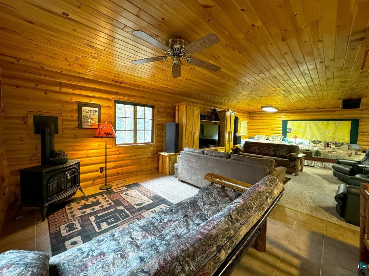 7236 Far North Road Orr, MN 55771 - Photo 25 of 42 Living area with wood ceiling, ceiling fan, tile patterned floors, and a wood stove