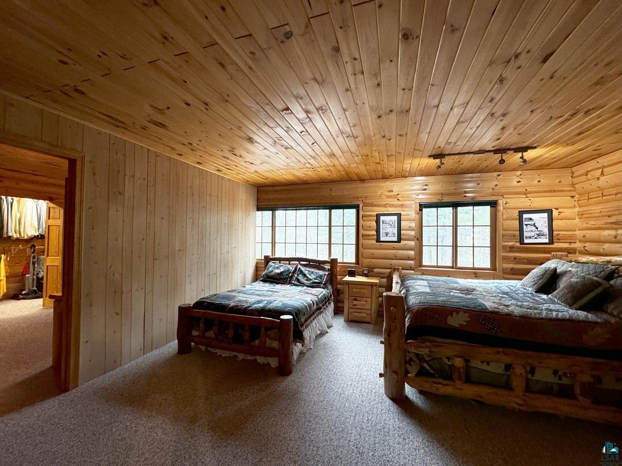7236 Far North Road Orr, MN 55771 - Photo 28 of 42 Bedroom with rail lighting, wooden ceiling, light carpet, and log walls