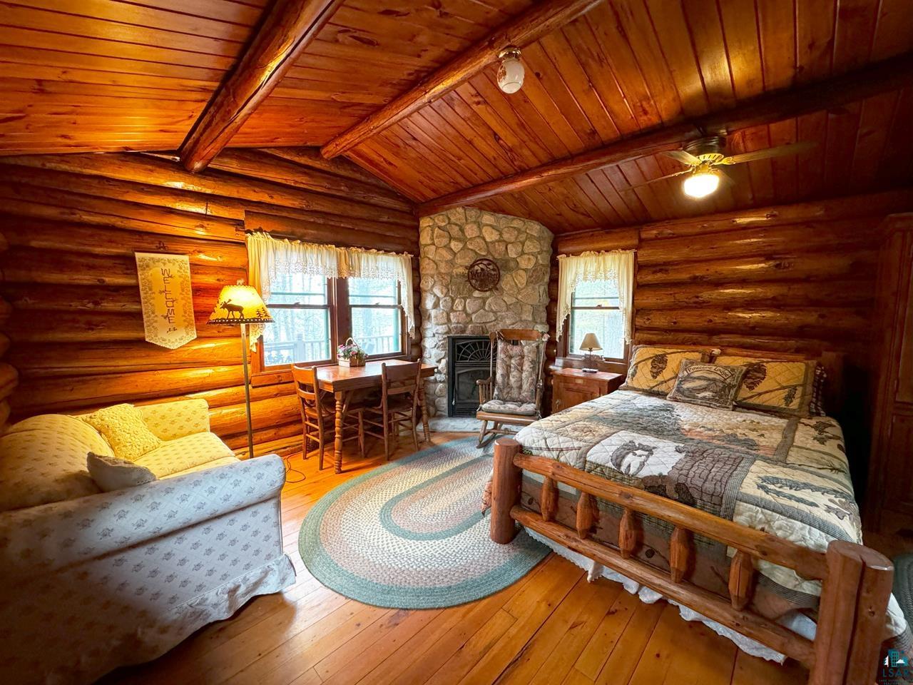 7236 Far North Road Orr, MN 55771 - Photo 37 of 42 Bedroom featuring wooden ceiling, rustic walls, hardwood / wood-style flooring, and a fireplace