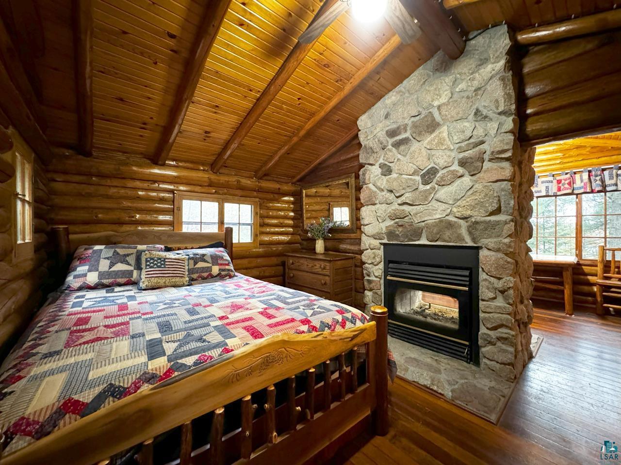 7236 Far North Road Orr, MN 55771 - Photo 38 of 42 Bedroom featuring log walls, multiple windows, beam ceiling, wooden ceiling, and wood-type flooring