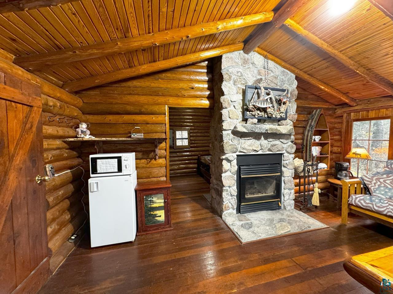 7236 Far North Road Orr, MN 55771 - Photo 39 of 42 Unfurnished living room featuring a stone fireplace, hardwood / wood-style flooring, and wooden ceiling