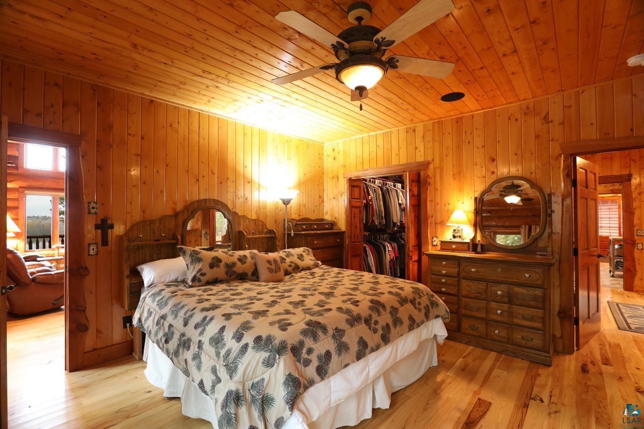 7236 Far North Road Orr, MN 55771 - Photo 9 of 42 Bedroom featuring wood ceiling, wood walls, light wood-type flooring, a closet, and a walk in closet