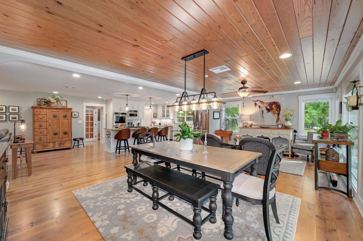 1020 River Road Wimberley, TX 78676 - Photo 16 of 40 a dining hall with stainless steel appliances kitchen island granite countertop a table and chairs with wooden floor
