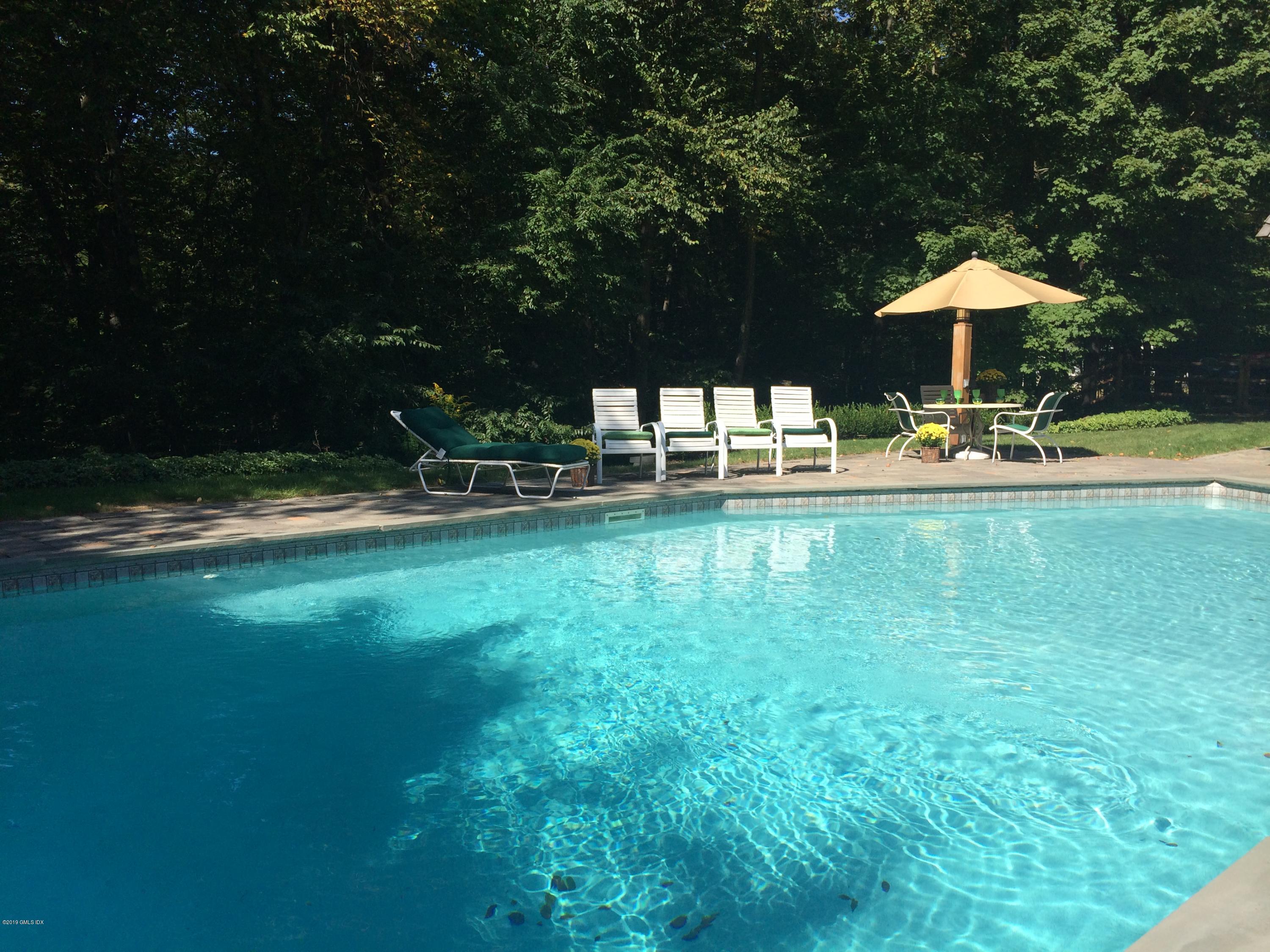 17 Heronvue Road Greenwich, CT 06831 - Photo 24 of 31 a backyard of a house with table and chairs under an umbrella