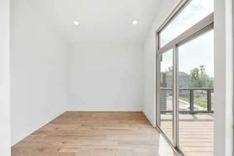 an empty room with wooden floor and windows
