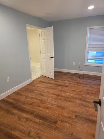 a view of empty room with window and wooden floor