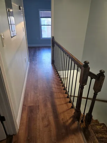 a view of a hallway with wooden floor and stairs
