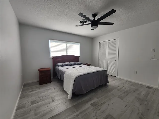 a spacious bedroom with a bed and a ceiling fan