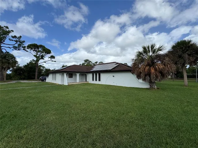a view of a house with a big yard potted plants and large tree
