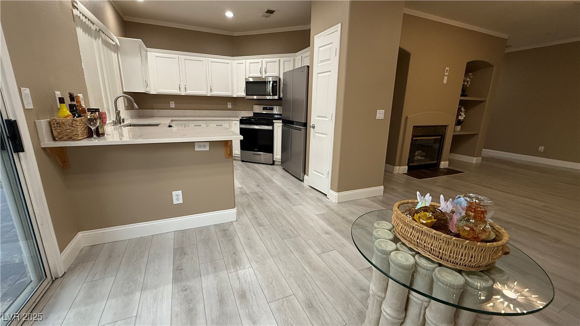 7062 Russell Ranch Avenue Las Vegas, NV 89113 - Photo 9 of 32 Kitchen with visible vents, a sink, ornamental molding, a peninsula, and stainless steel appliances