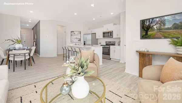 a living room with furniture a dining table and kitchen view with wooden floor