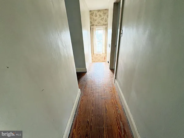 a view of a hallway with wooden floor and a bathroom