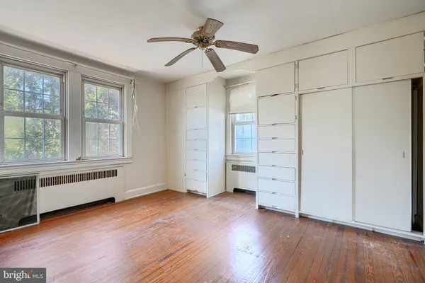 an empty room with wooden floor cabinet and windows