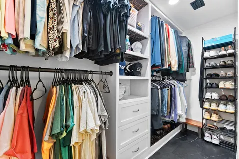 a view of walk in closet with clothes and shoes