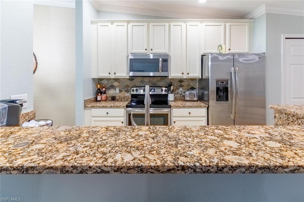 9828 Venezia Circle, Unit 1124 Naples, FL 34113 - Photo 12 of 50 a kitchen with kitchen island granite countertop a refrigerator oven a stove and a sink