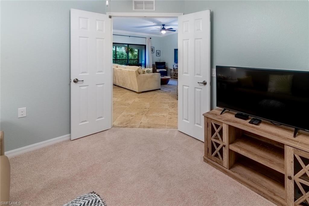 9828 Venezia Circle, Unit 1124 Naples, FL 34113 - Photo 15 of 50 a room with furniture and flat screen tv