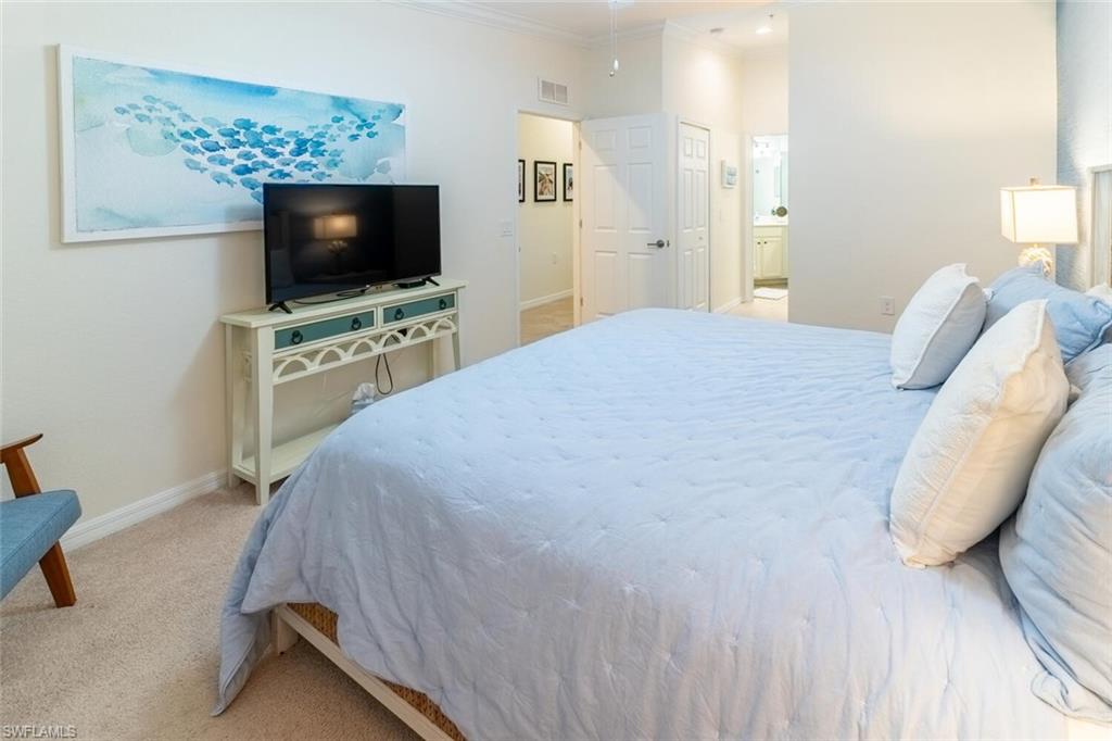 9828 Venezia Circle, Unit 1124 Naples, FL 34113 - Photo 18 of 50 a bedroom with a flat screen tv and a bed