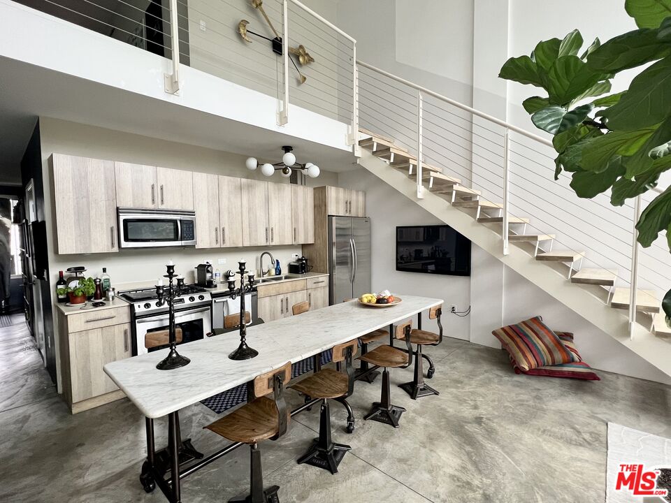 a kitchen with stainless steel appliances kitchen island granite countertop a refrigerator a stove a sink dishwasher and white cabinets with wooden floor