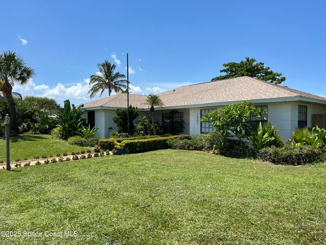 a view of a white house with a yard table and chairs under an umbrella