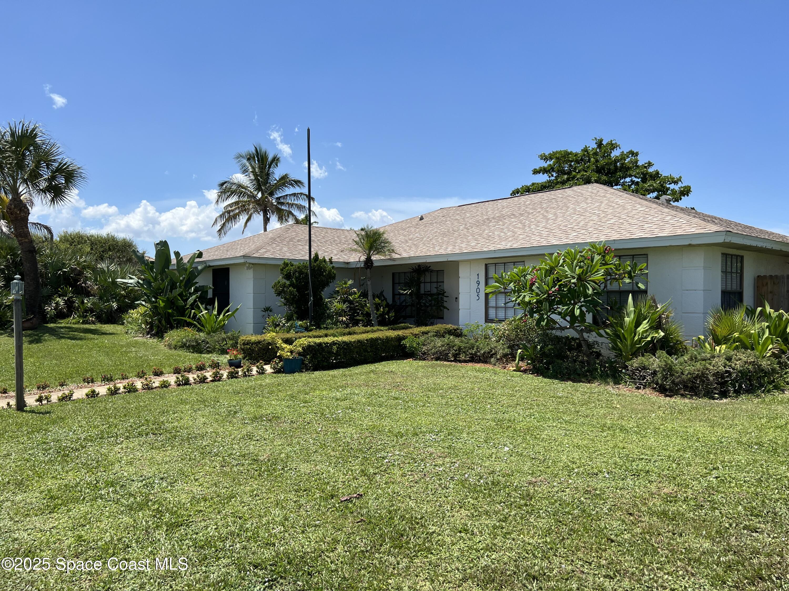 a view of a white house with a yard table and chairs under an umbrella