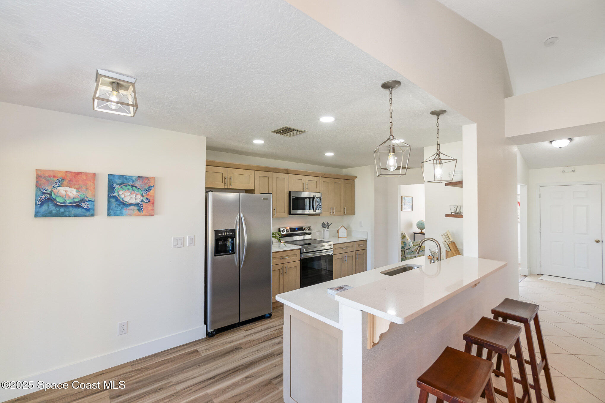 1905 Redwood Avenue Melbourne Beach, FL 32951 - Photo 2 of 15 a large kitchen with a refrigerator a stove a sink a dining table and chairs with wooden floor