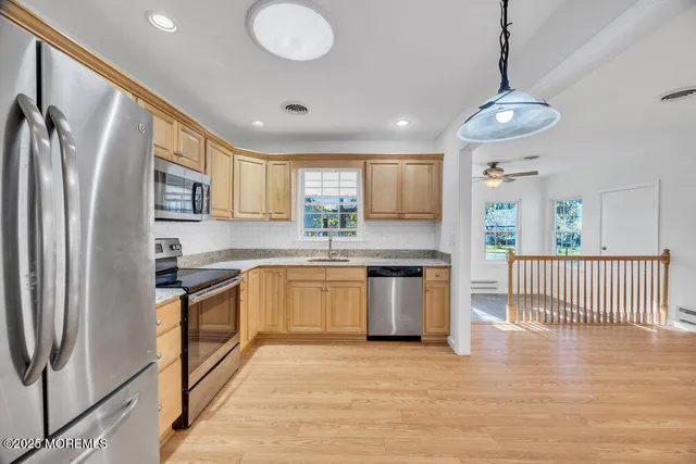 a kitchen with stainless steel appliances granite countertop a refrigerator a sink dishwasher a stove and white countertops with wooden floor