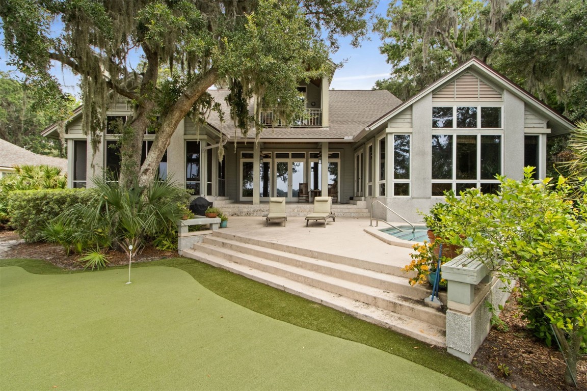 10 Sea Marsh Road Amelia Island, FL 32034 - Photo 49 of 78 a view of a white house with a large pool and a lawn chairs under a large tree