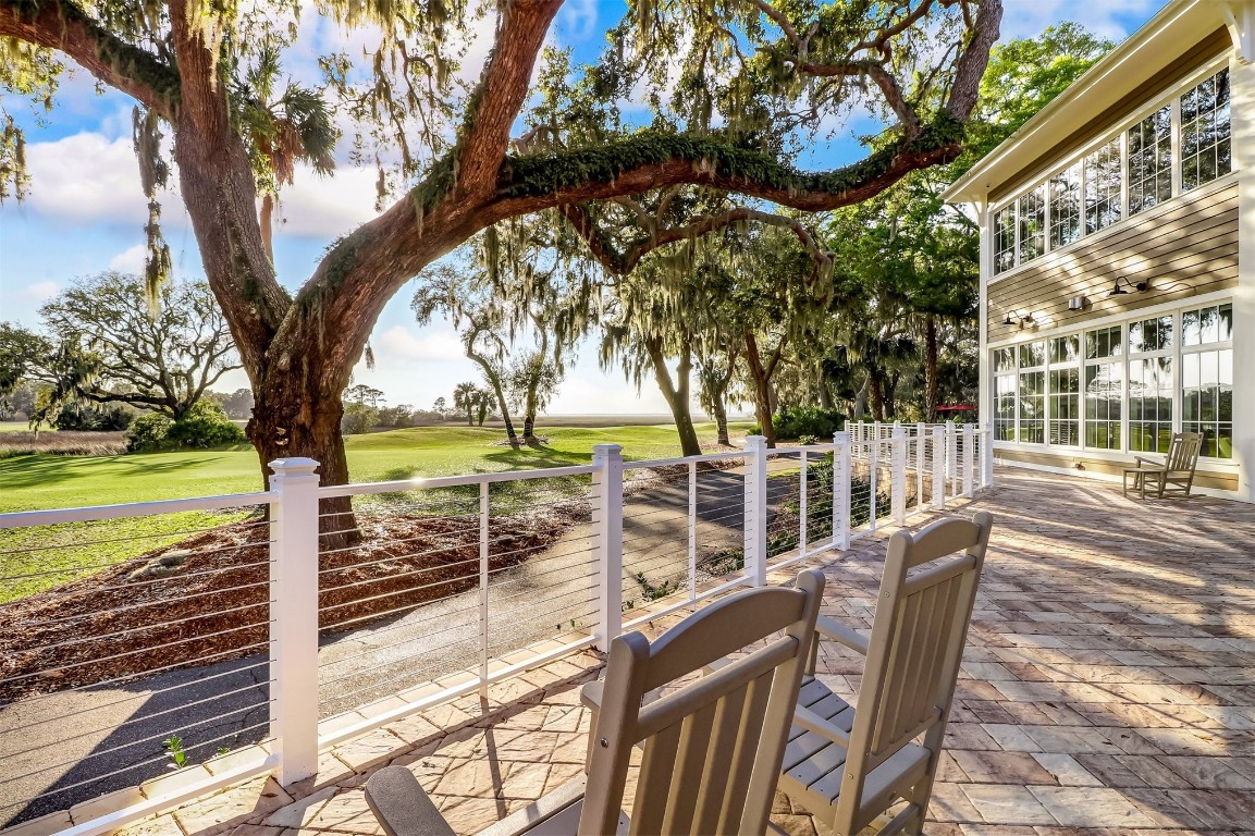 10 Sea Marsh Road Amelia Island, FL 32034 - Photo 77 of 78 a view of a patio with table and chairs next to a yard with a large tree