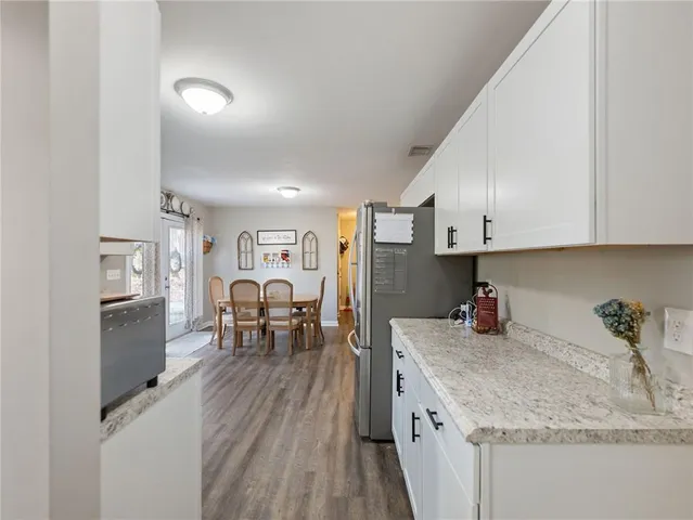 a kitchen with stainless steel appliances granite countertop a refrigerator a sink dishwasher a stove and a dining table with wooden floor