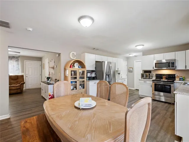 a living room with furniture kitchen view and wooden floor