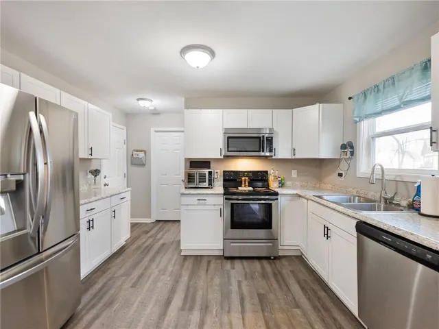 a kitchen with cabinets stainless steel appliances a sink and a window