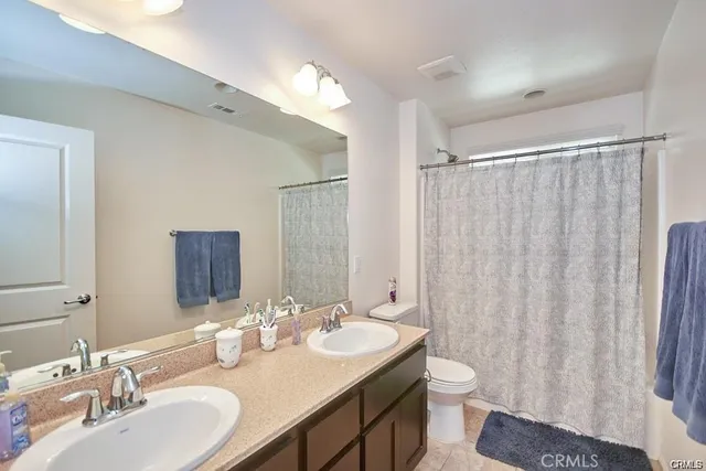 a bathroom with a double vanity sink toilet and a mirror
