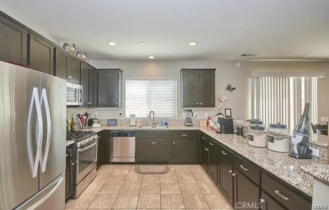 a large kitchen with granite countertop lots of counter top space sink and stainless steel appliances