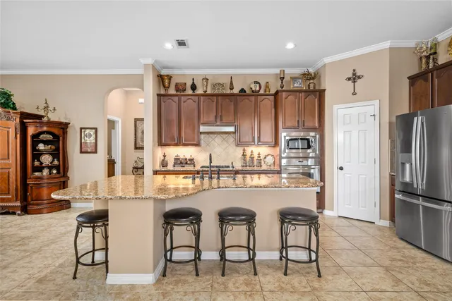 a kitchen with stainless steel appliances kitchen island granite countertop a refrigerator and cabinets