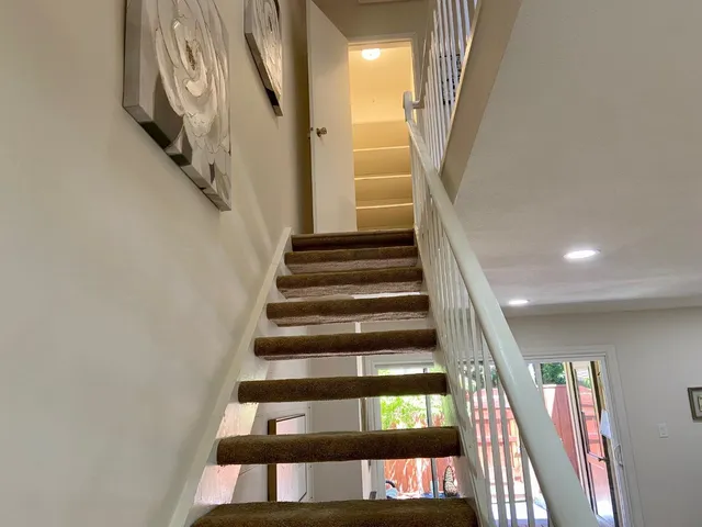 a view of staircase with lots of frames on wall and a window