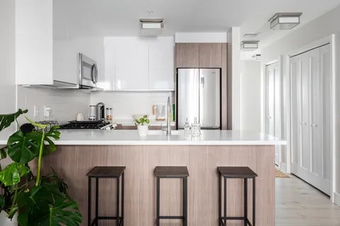 a kitchen with stainless steel appliances granite countertop white cabinets a refrigerator and a sink