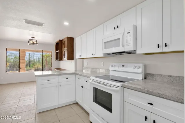 a view of an empty room with window and kitchen area