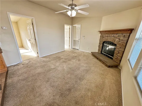 a view of a livingroom with a fireplace a ceiling fan and window